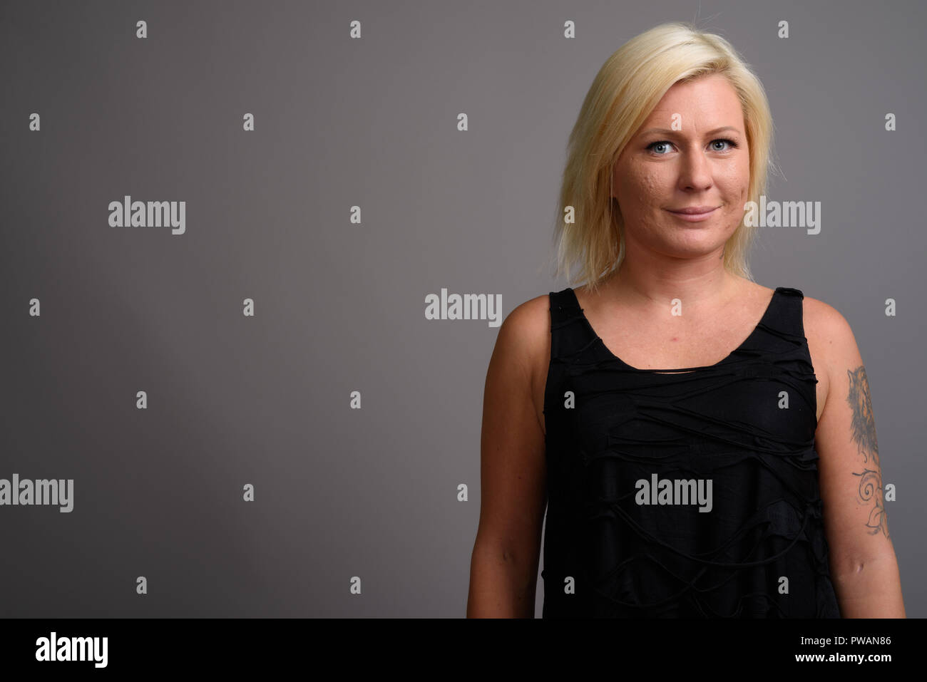 Portrait de femme aux cheveux blonds contre l'arrière-plan gris Banque D'Images