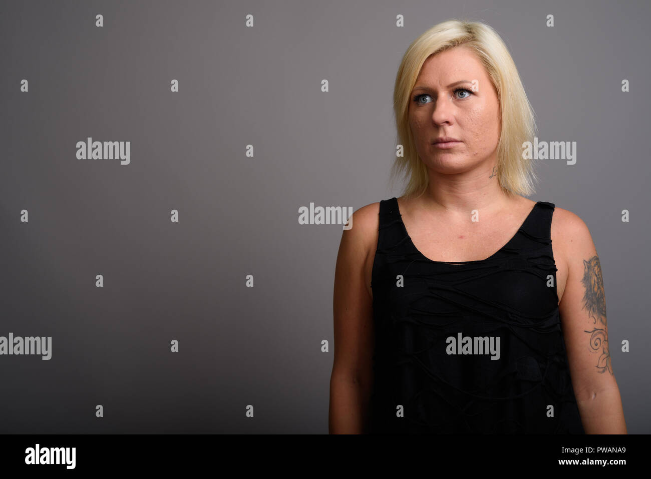 Portrait de femme aux cheveux blonds contre l'arrière-plan gris Banque D'Images