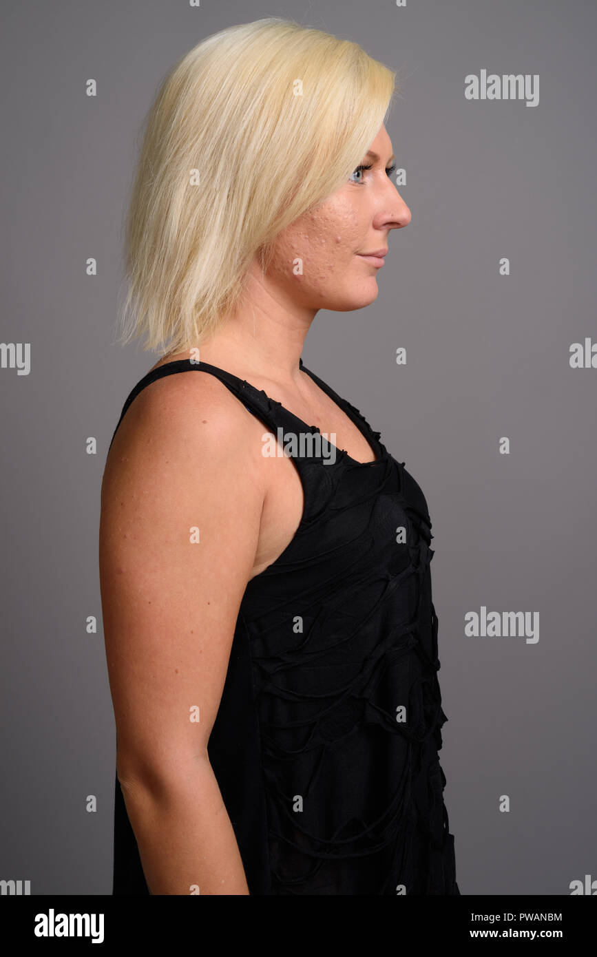 Portrait de femme aux cheveux blonds contre l'arrière-plan gris Banque D'Images