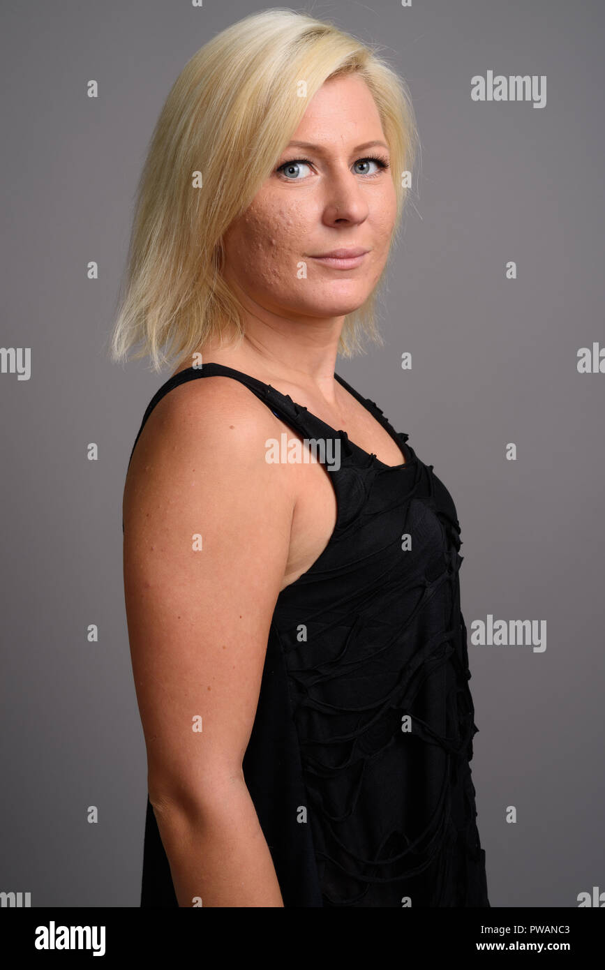 Portrait de femme aux cheveux blonds contre l'arrière-plan gris Banque D'Images