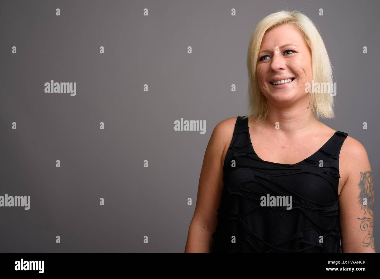 Portrait de femme aux cheveux blonds contre l'arrière-plan gris Banque D'Images