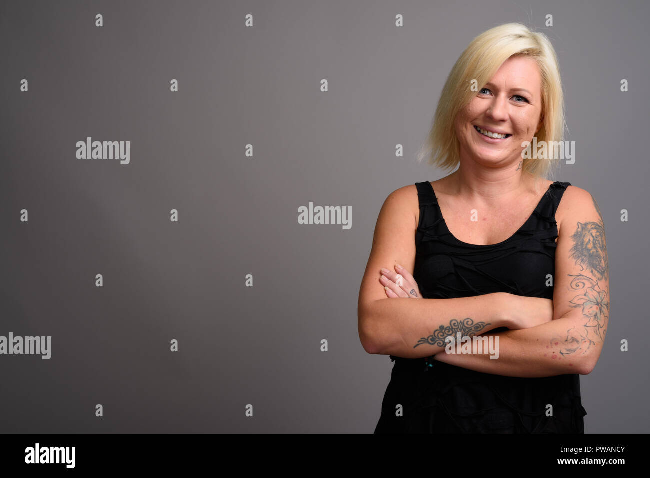 Portrait de femme aux cheveux blonds smiling contre l'arrière-plan gris Banque D'Images
