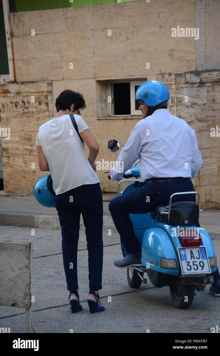 Un couple sur un vespa bleu avec des casques bleus Tirana Albanie Banque D'Images