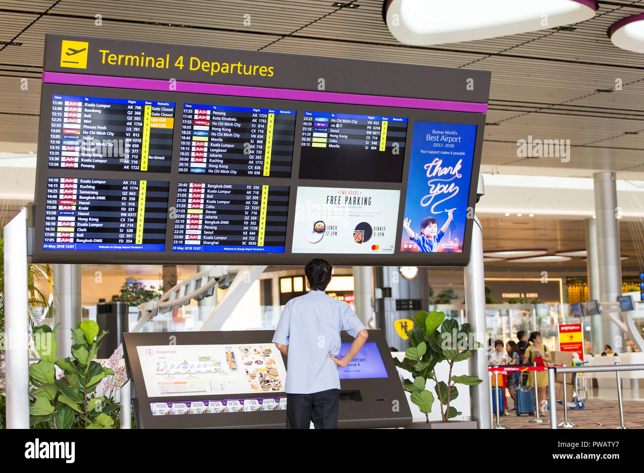 Un homme de l'aéroport de Changi Terminal 4 système d'affichage d'information de vol de lignes aériennes de distribution de départ. T4 est la plus récente s'ouvre dans l'aéroport en 2018. Banque D'Images