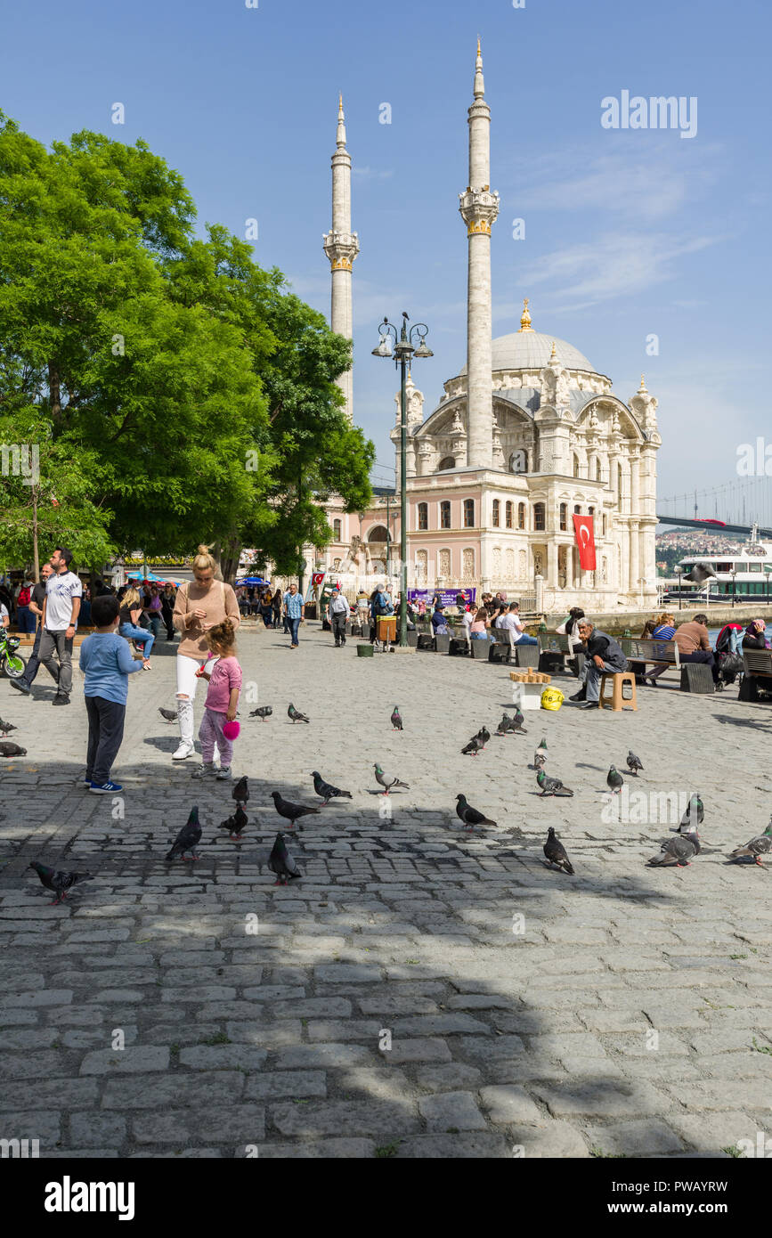 Une mère et ses enfants se nourrir les pigeons avec le style baroque et la mosquée Ortaköy Bosphore en arrière-plan, Istanbul, Turquie Banque D'Images