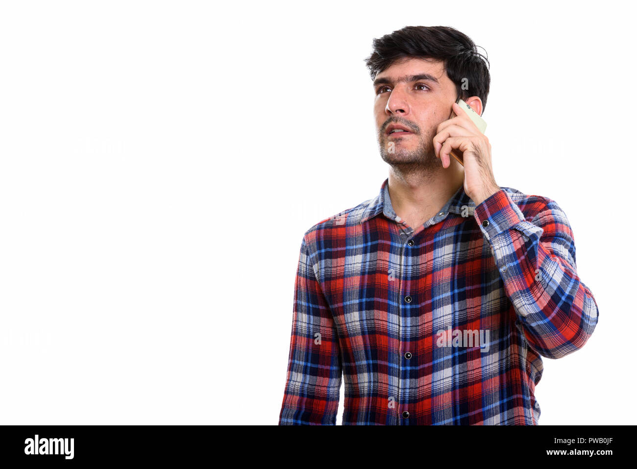 Persan Studio shot of young man talking on mobile phone alors que t Banque D'Images