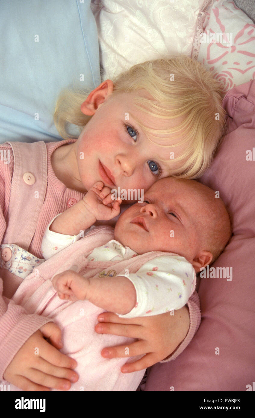 Little girl holding sa sœur bébé nouveau-né Banque D'Images