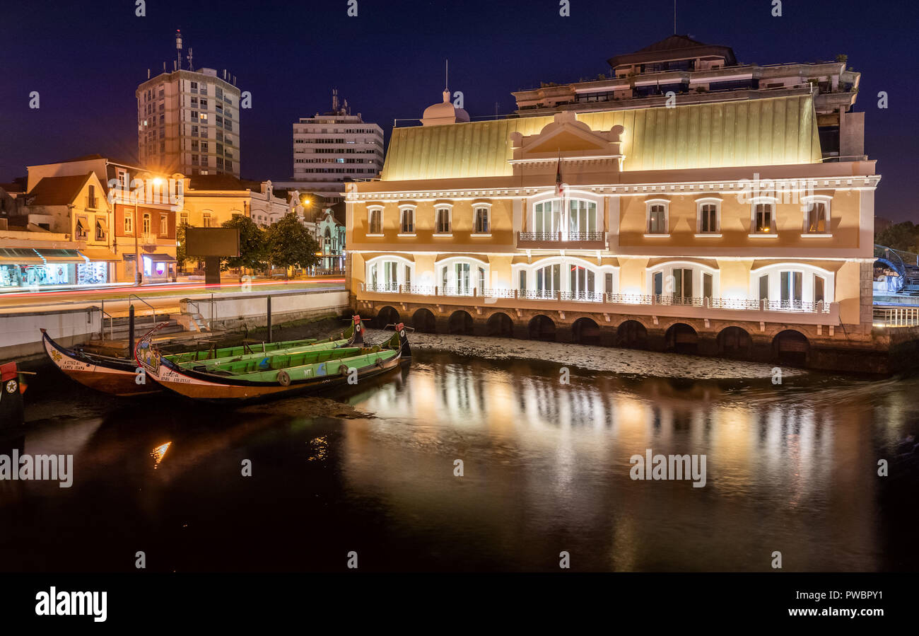 Vue sur le canal central d'Aveiro la nuit avec moliceiros amarré et le bâtiment éclairé. Centre-ville d'Aveiro au Portugal. Banque D'Images