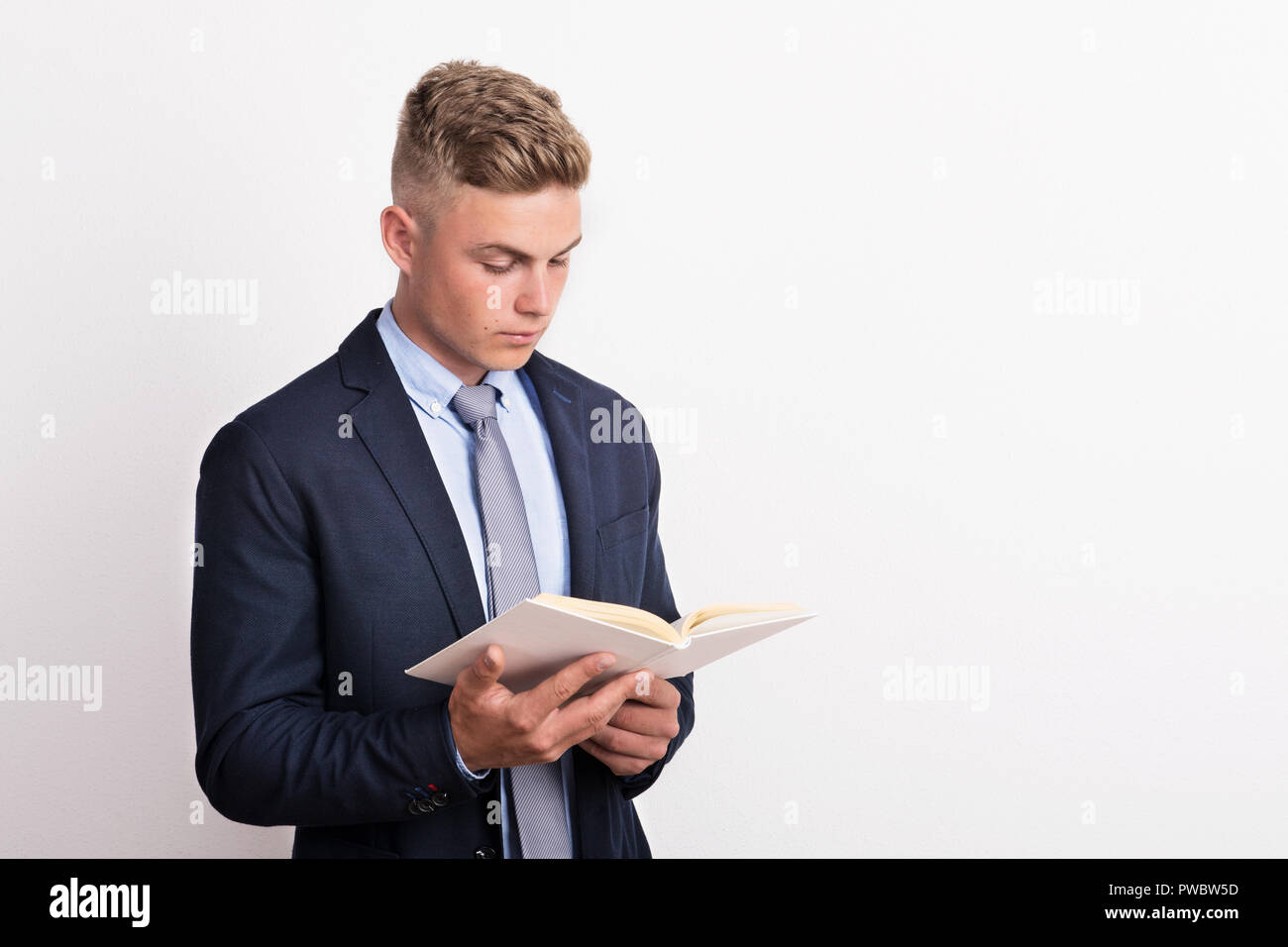 Portrait d'un jeune homme dans un studio, la tenue et la lecture d'un livre. Copier l'espace. Banque D'Images