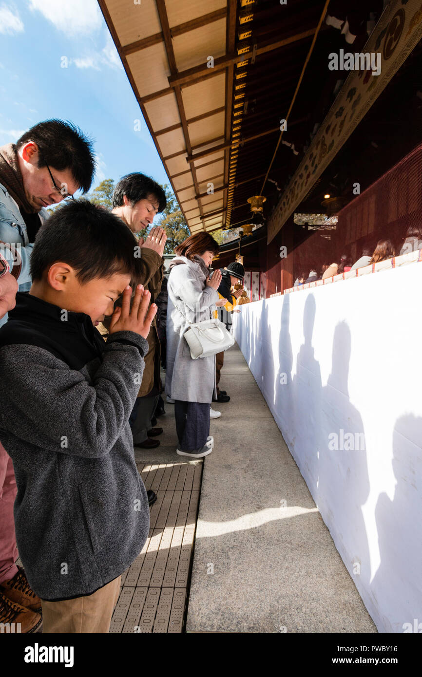 Nouvel An japonais, shogatsu. Enfant, 6-7 ans avec les gens priaient à la peur dans le hall principal, l'Honden des Shinto Nishinomiya. Banque D'Images