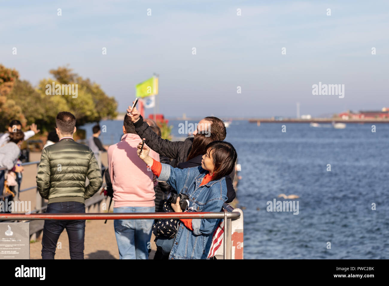 Les touristes en tenant vos autoportraits par la Petite Sirène (non représenté) à Copenhague, Danemark Banque D'Images