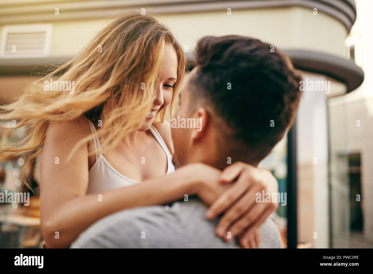 Jeune couple hugging et se regarder dans les yeux tout en partageant un moment romantique dans une rue de la ville Banque D'Images