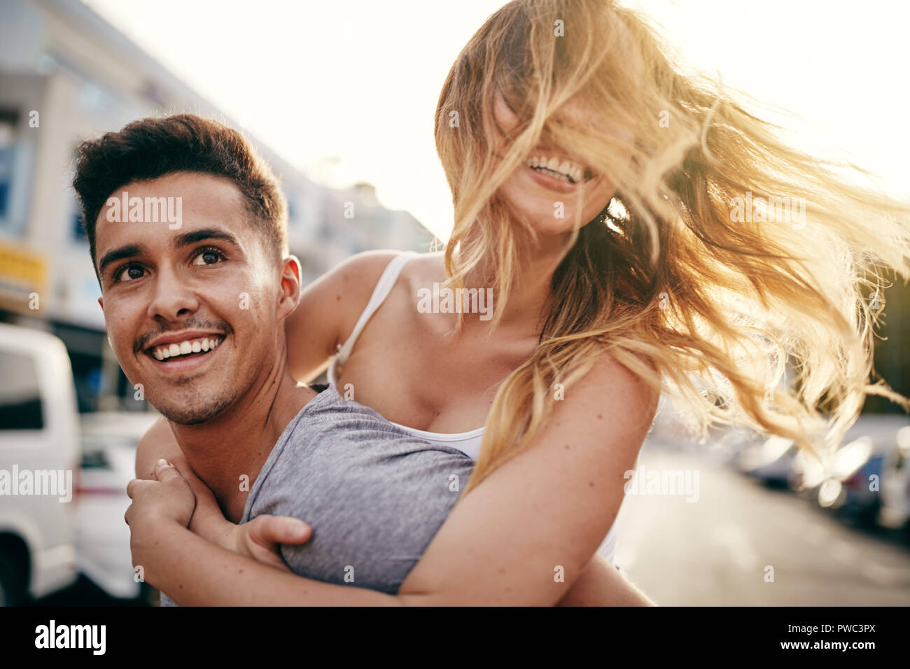 Jeune femme rire étant pris par son petit ami tout en profitant d'une journée ensemble dans la ville Banque D'Images