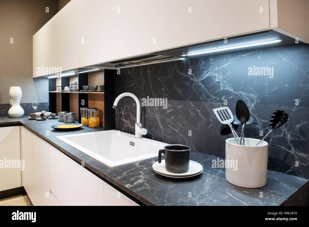 En effet comptoir de la cuisine avec des ustensiles et un évier rectangulaire blanc en dessous des armoires murales et splash back Banque D'Images