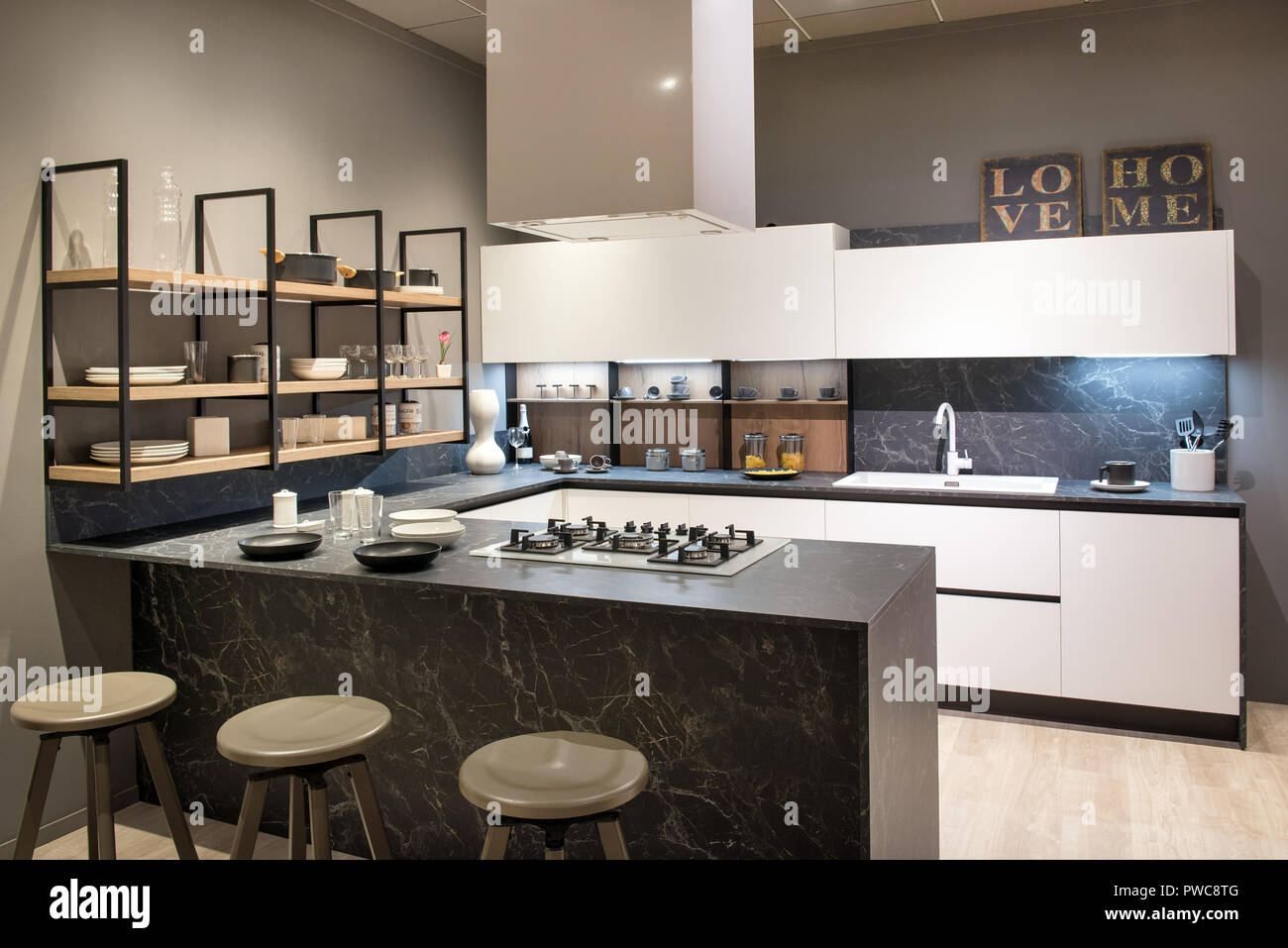 L'intérieur d'une cuisine moderne avec îlot central avec tabourets de bar et table de cuisson, armoires et étagères ouvertes blanc Banque D'Images