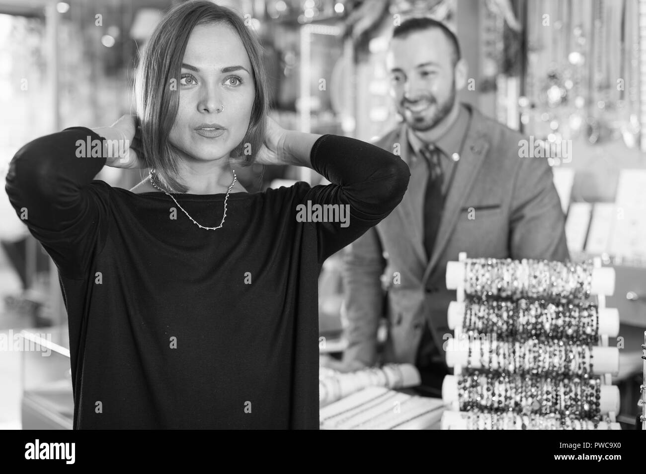 La consommation des femmes essayant chaînette avec pendentifs en bijouterie Banque D'Images