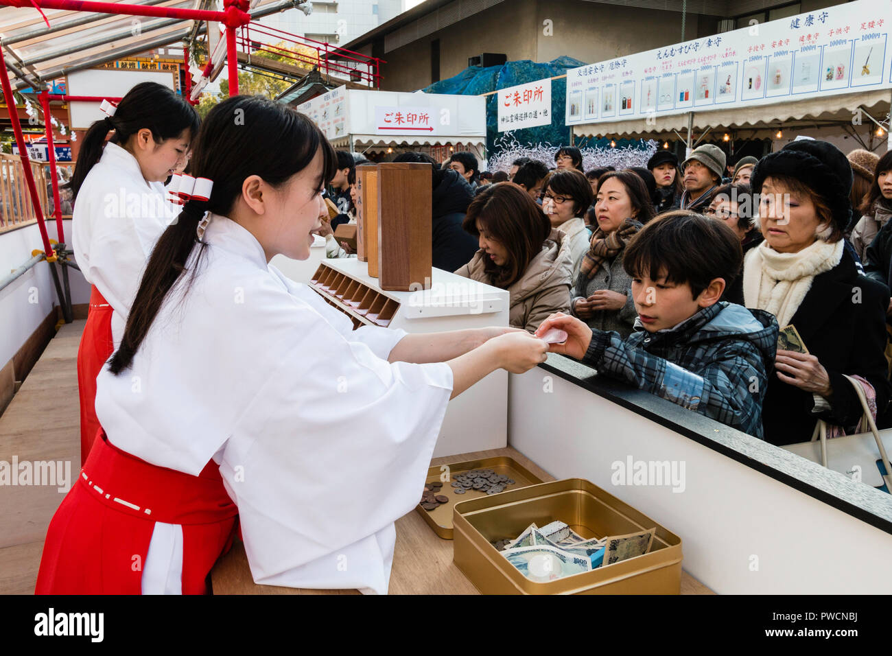 Nouvel An japonais, shogatsu. Shrine Maidens, Miko, occupé à lutter contre la vente de papier des feuillets d'omikuji fortune à Ikuta Temple Shinto à Kobe. Banque D'Images