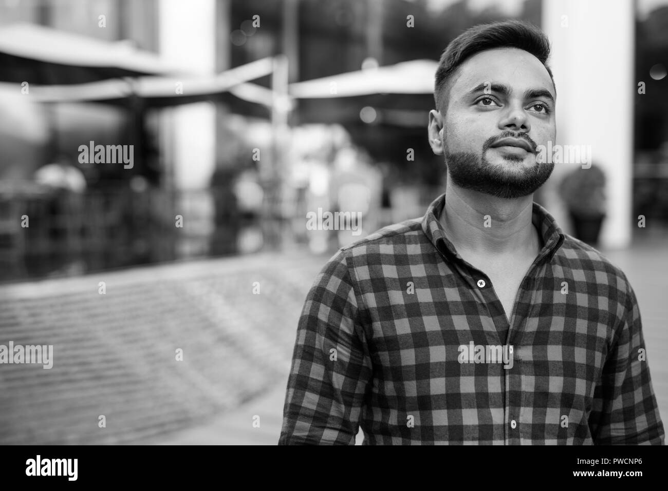 Jeune homme d'affaires indien barbu se détendre au centre commercial à Bangkok Banque D'Images