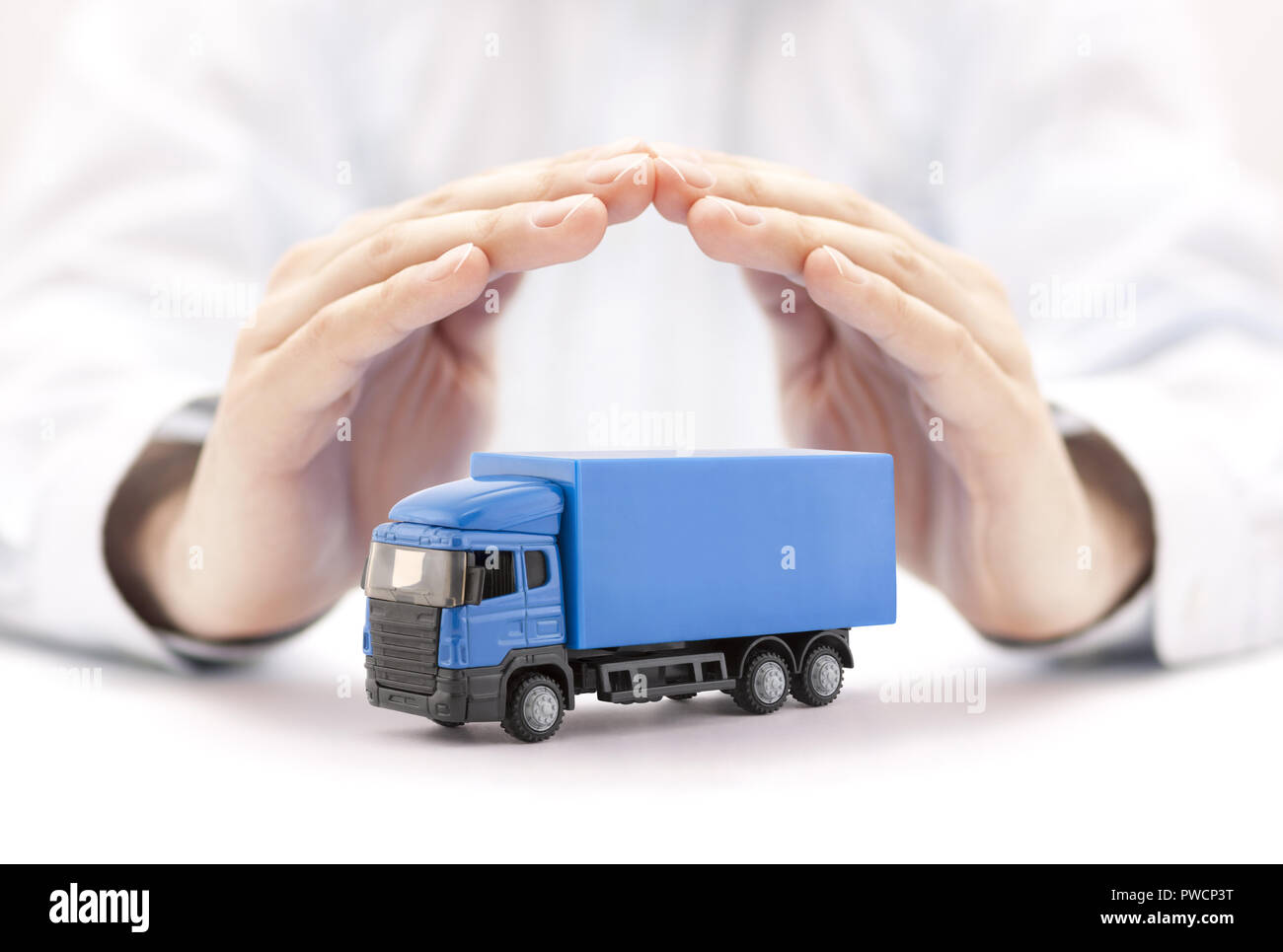 Assurance auto. Miniature camion bleu couverts par les mains. Banque D'Images