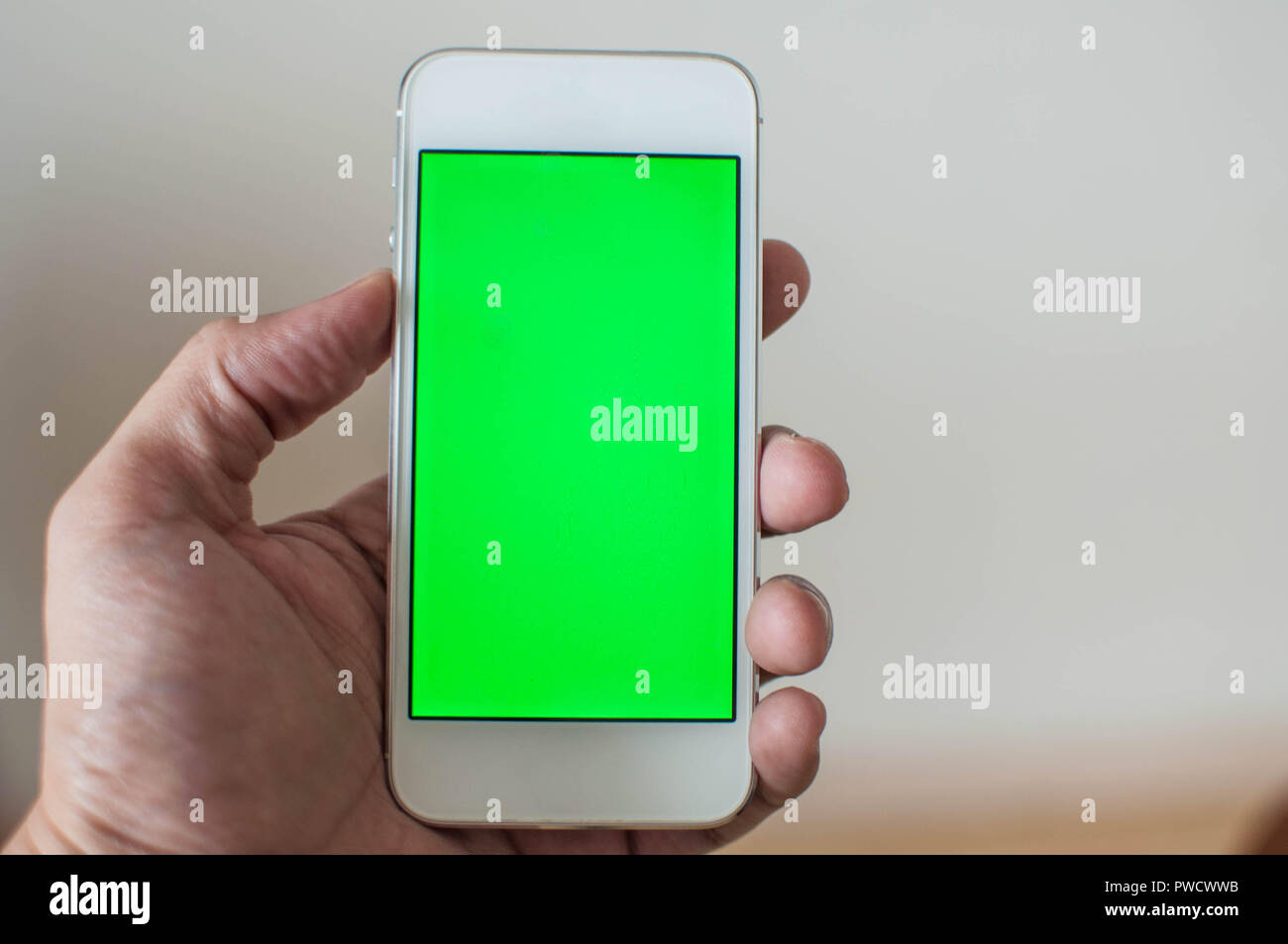 Jeune homme tenant un téléphone intelligent avec écran vert Banque D'Images