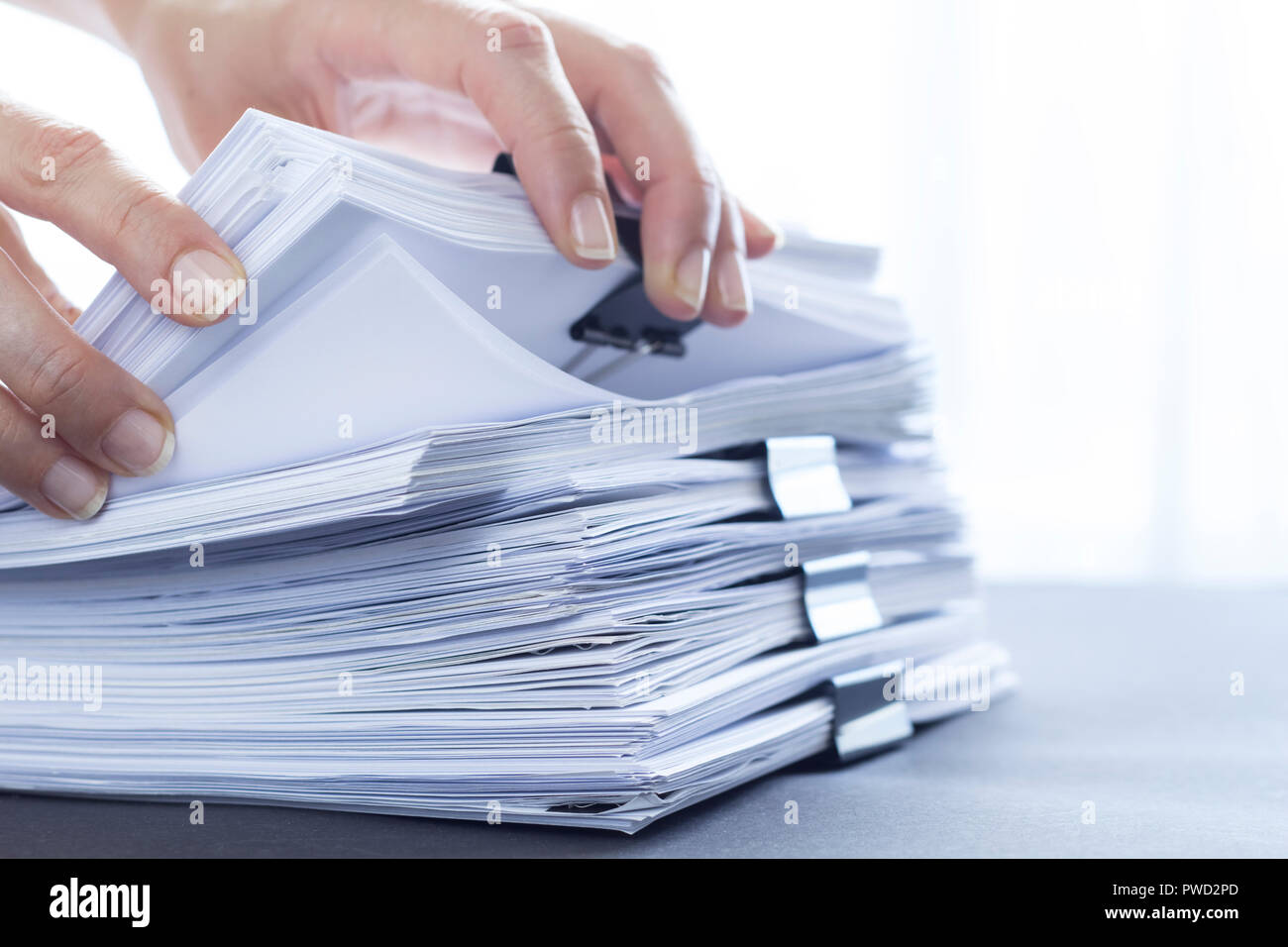 Les mains de toucher le papier de bureau. Les fichiers documents piles noir avec clip. Banque D'Images