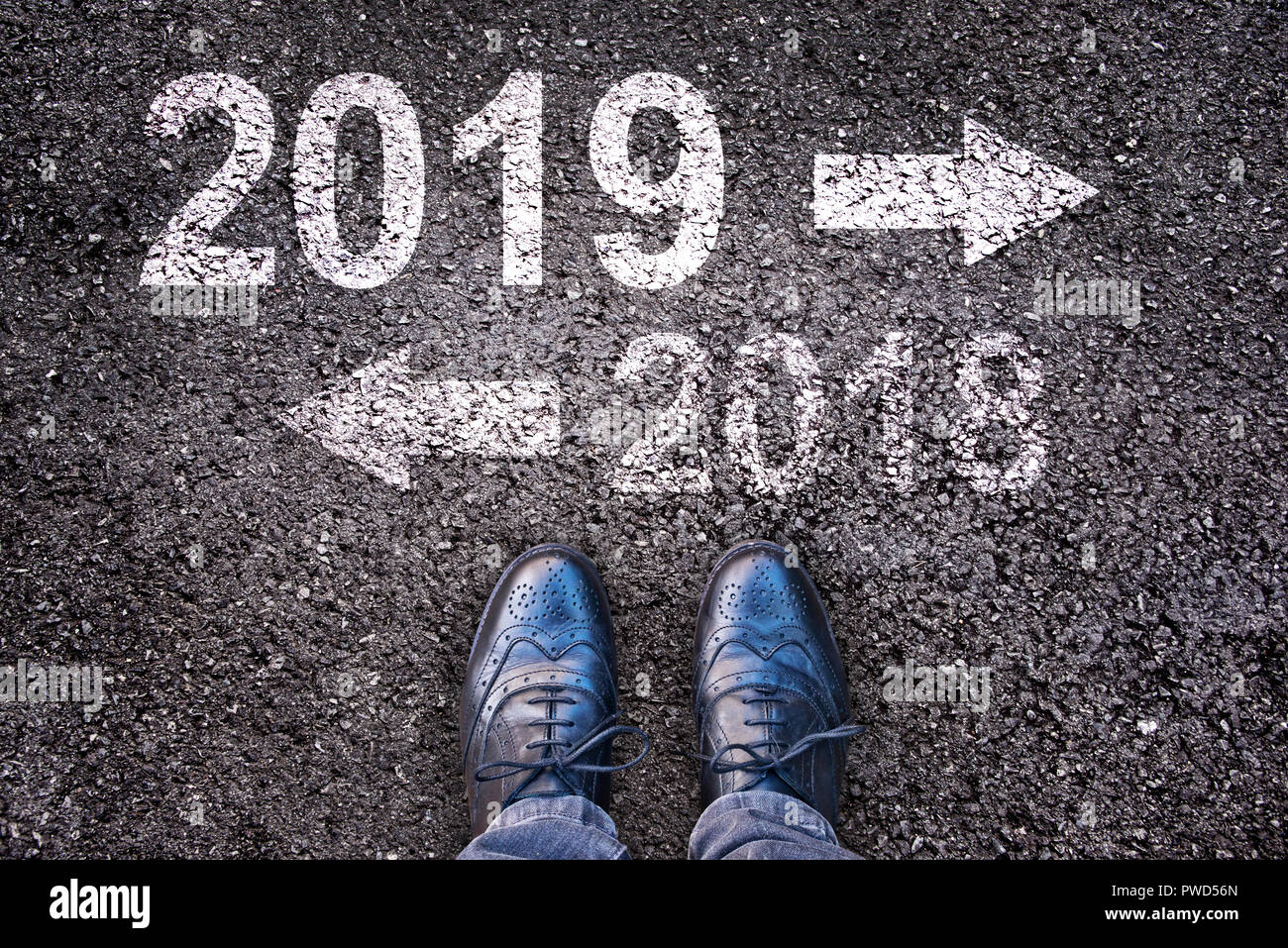 2019 et une flèche écrit sur une route asphaltée, les jambes en arrière-plan Banque D'Images