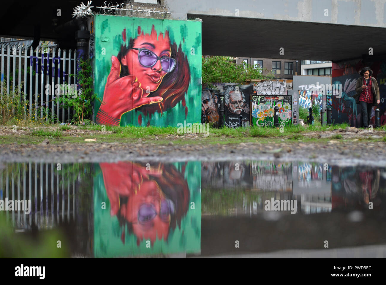 Shoreditch street art reflète dans une flaque à la fin de l'été. Banque D'Images