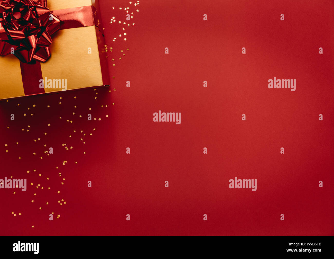 Boîte cadeau dorée avec des étoiles sur fond rouge. Vue de dessus de cadeau de Noël avec étoiles jeter sur fond rouge. Banque D'Images