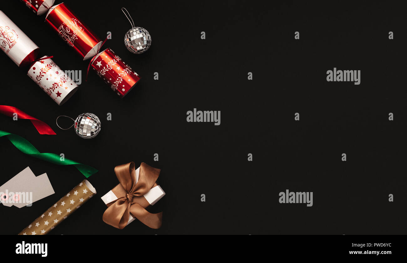 Mise à plat de décoration de Noël sur fond noir. Tourné directement au-dessus des cloches de Noël, boules, des rubans colorés, tags et boîte-cadeau avec c Banque D'Images