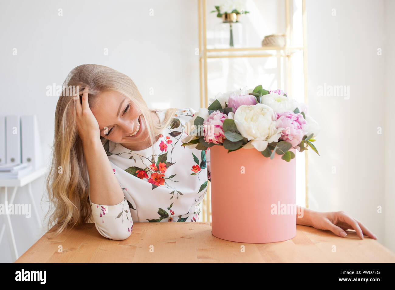 Happy Blonde Femme Dans Un Bureau Moderne Avec Des Fleurs Dans Une Boite A Chapeau Bouquet De Pivoines Livraison De Fleurs Au Milieu De Travail Photo Stock Alamy