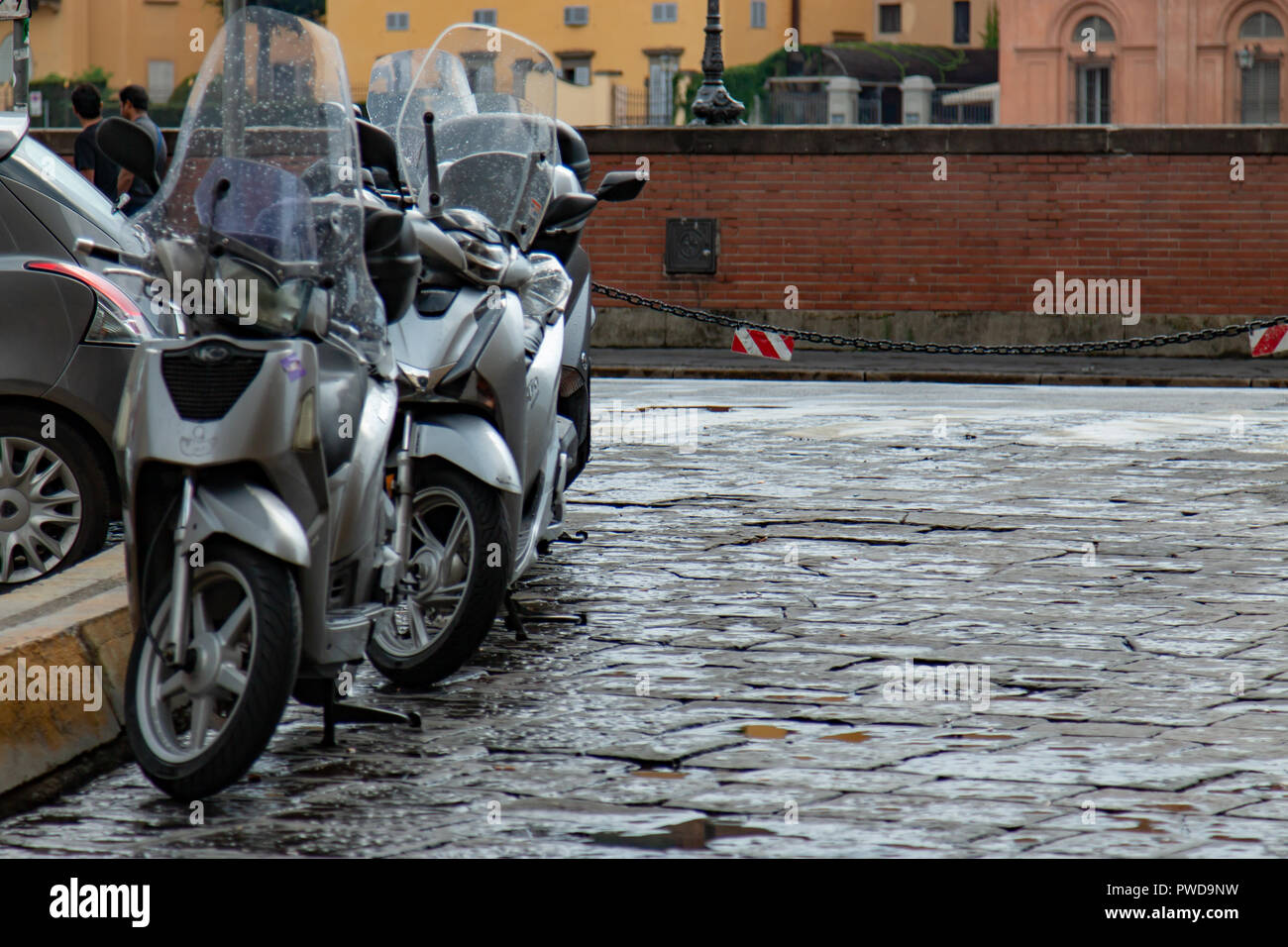 Moto garée à côté d'un trottoir le long de la rivière à Florence, Italie. Banque D'Images