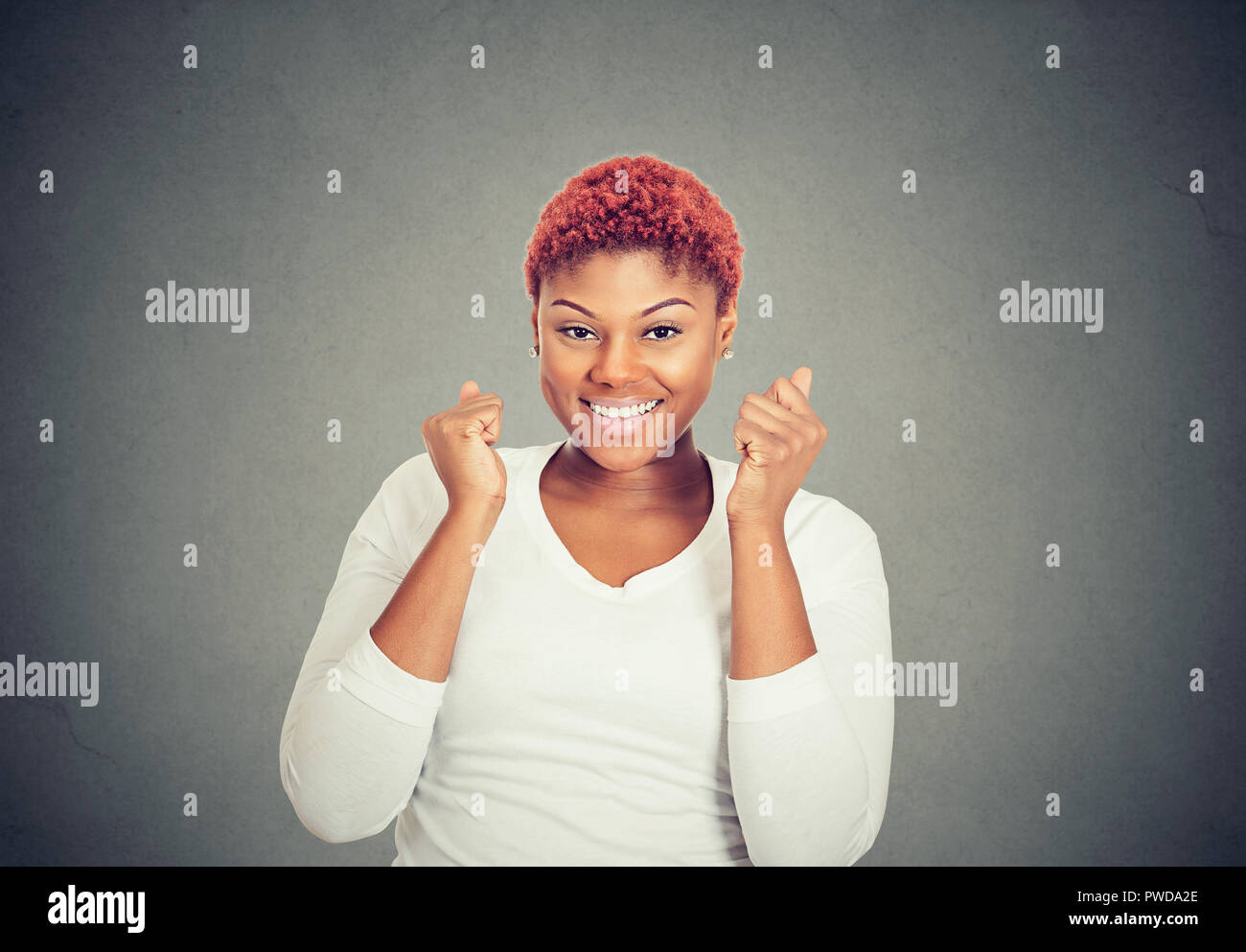 Super excitée Jeune femme tenant les poings jusqu'à l'occasion de succès sur fond de mur gris Banque D'Images