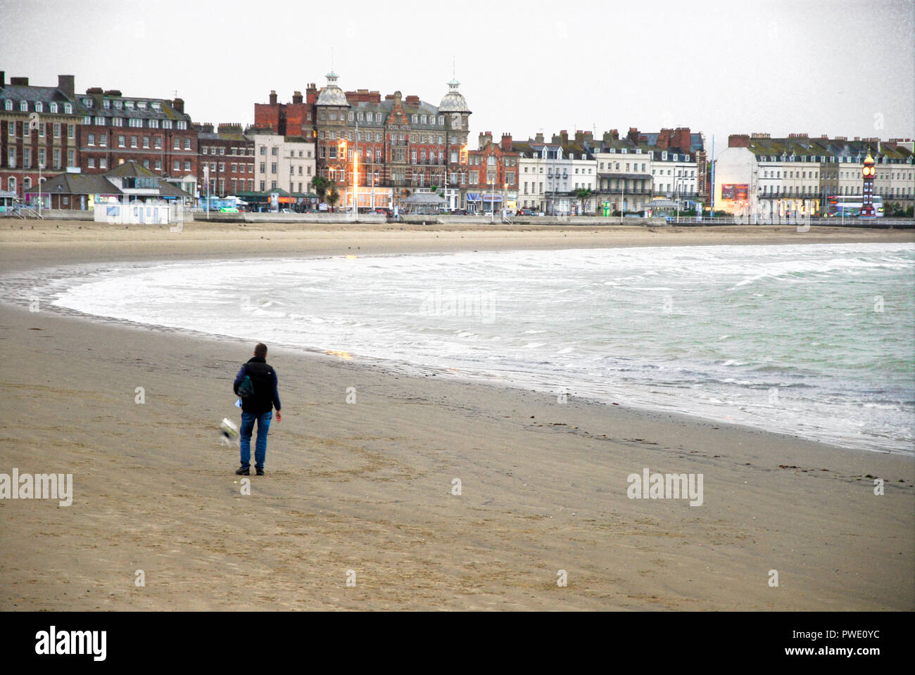 Weymouth. 15 octobre 2018. Un homme solitaire promène son chien sur terne et sables de la bruine tôt le matin Crédit : Stuart fretwell/Alamy Live News Banque D'Images