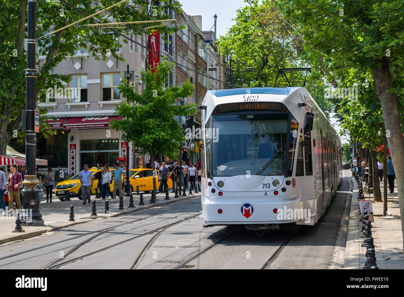 Un Kabatas-Bagcilar T1 tramway Métro électrique descend dans un boulevard passé les bâtiments et les personnes dans le district de Fatih de la Corne d'or, Istanbul, Turke Banque D'Images