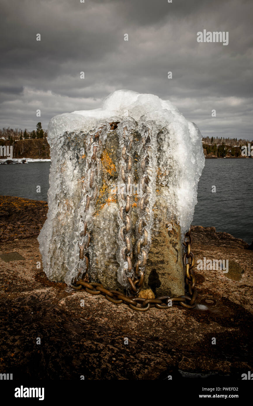 Les vagues de tempête au début du printemps une robe la rive de Gooseberry Falls State Park dans une couche de glace. Banque D'Images