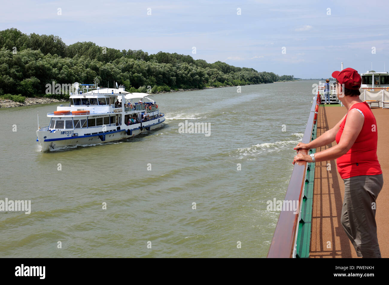 Le comté de Tulcea, Roumanie, Dobroudja, Dobroudja, Réserve de biosphère du delta du Danube, Delta du Danube, delta de rivière, estuaire, embouchure de la rivière du Danube à la mer Noire, du Danube river cruise, Danube, navigation sur l'aROSA cruiser Mia Direction de Sulina Sulina entre le Danube et la jeune femme se dresse, Maliuc sur les ponts supérieurs garde-fous en prenant soin d'un petit navire d'excursion touristique, tourisme, paysage, rivière Danube, paysage, rive du Danube, Woodland, UNESCO World Heritage Site, repère naturel Banque D'Images