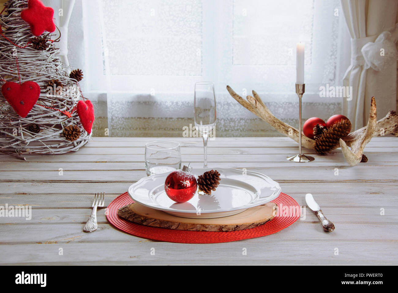Lieu de Noël blanc avec vaisselle, couverts, vaisselle et décorations rouge blanc sur planche de bois. Chandelier de Noël bougies rouges avec comme décor. Banque D'Images