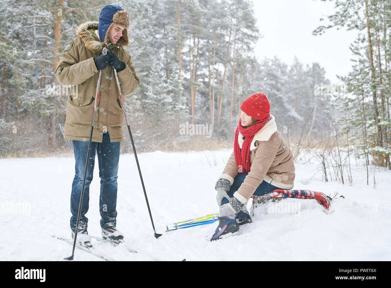 Portrait de jeune couple actif le ski en hiver sur Forest focus woman rubbing entorse à la cheville et à la recherche au petit ami, copy space Banque D'Images