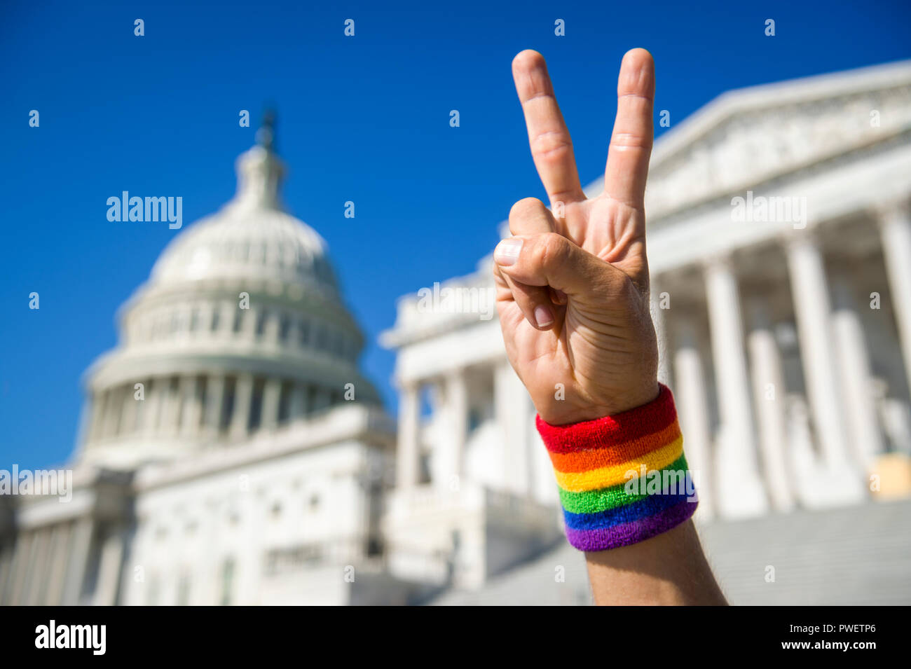 La main avec gay pride bracelet arc-en-ciel faisant un signe de la paix devant le Capitole à Washington, DC, USA Banque D'Images
