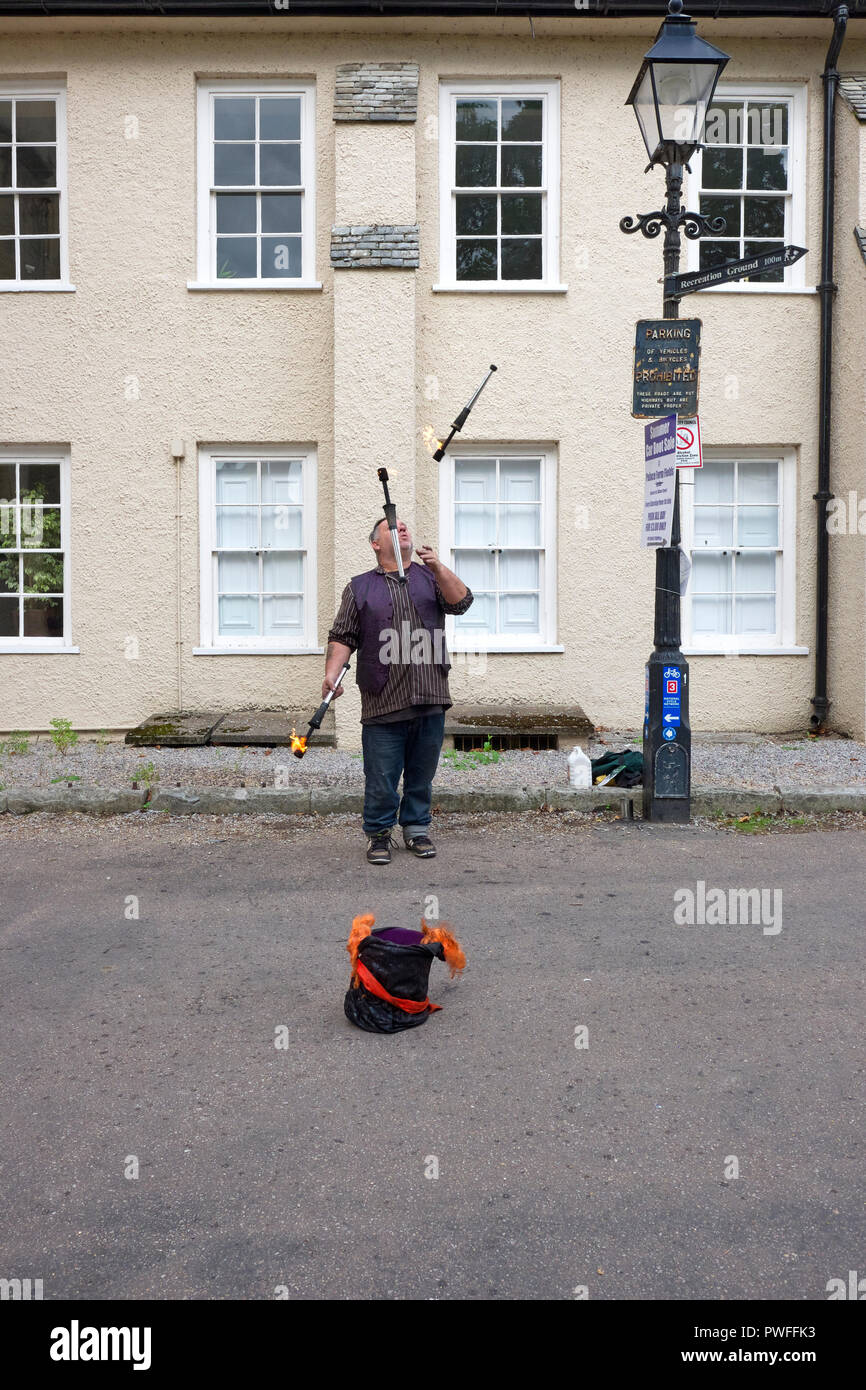 Artiste de rue jonglant avec des torches enflammées sur la Palace Green à Bishop's Palace. Wells, Somerset, UK Banque D'Images