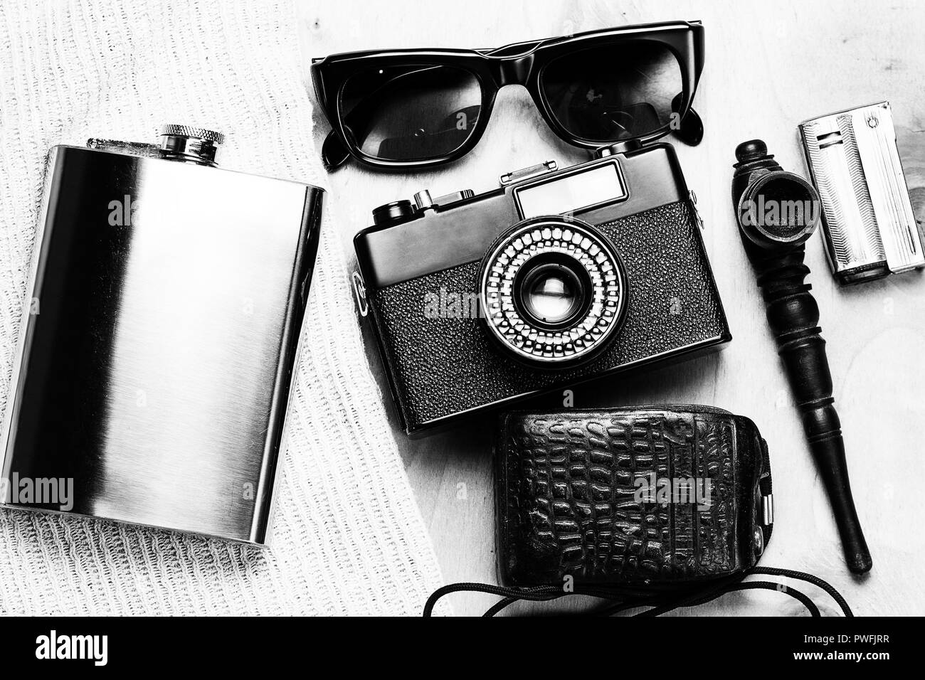Accessoires de la personne créative. 35-mm, mesure d'exposition en cas de cuir, d'acier, des lunettes de soleil et fiole fumeurs mis sur fond de bois. Banque D'Images