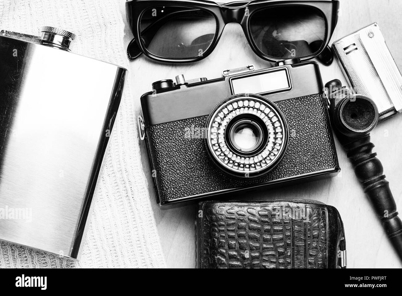 Accessoires de la personne créative. 35-mm, mesure d'exposition en cas de cuir, d'acier, des lunettes de soleil et fiole fumeurs mis sur fond de bois. Banque D'Images