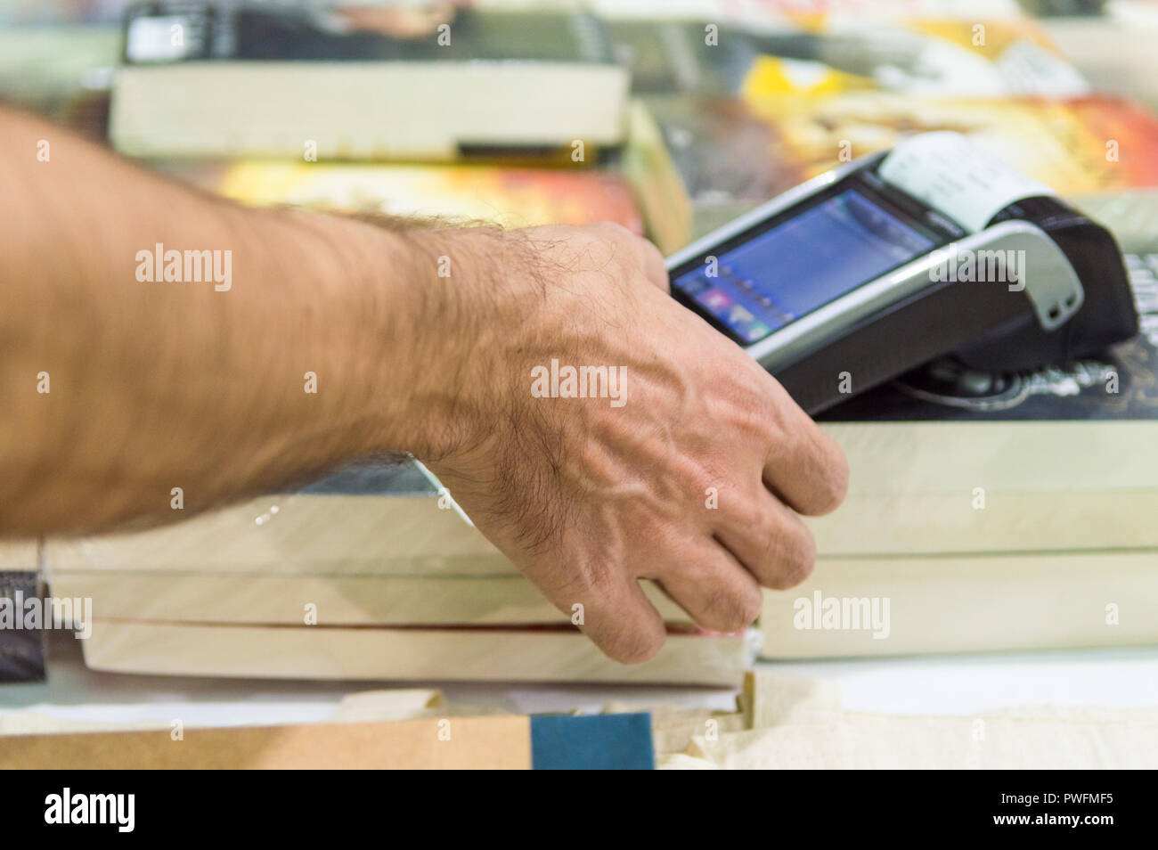 Close up of male hand en utilisant le balayage de carte de crédit pour payer la machine. Carte de crédit homme entrant dans le POS code machine dans un magasin de livre. Banque D'Images
