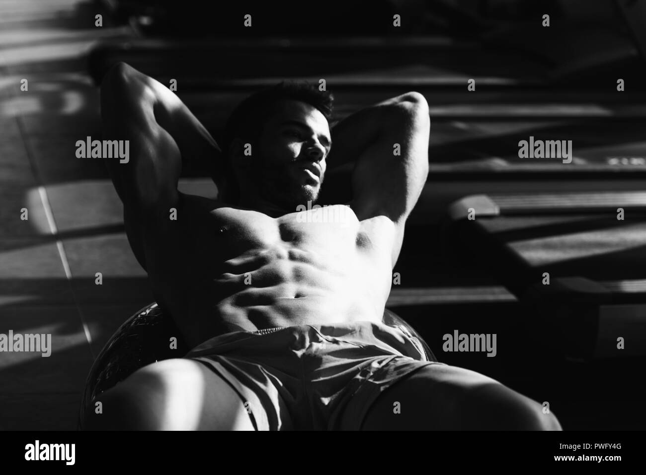 Jeune homme sportif faisant l'exercice ABS sur la bille dans le cadre de la formation de culturisme Banque D'Images