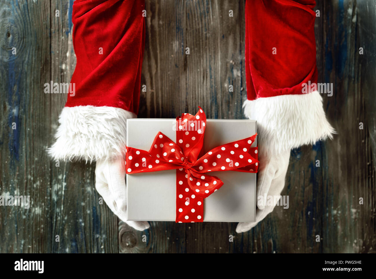 Vue de dessus de Santa's hands holding cadeau de Noël sur fond de bois Banque D'Images