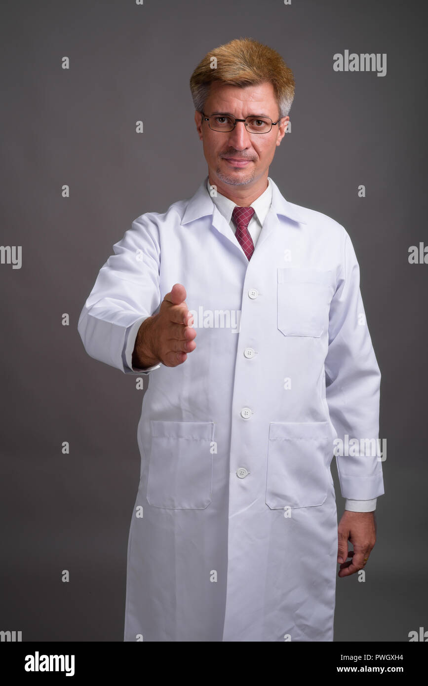 Médecin de l'homme aux cheveux blonds contre l'arrière-plan gris Banque D'Images