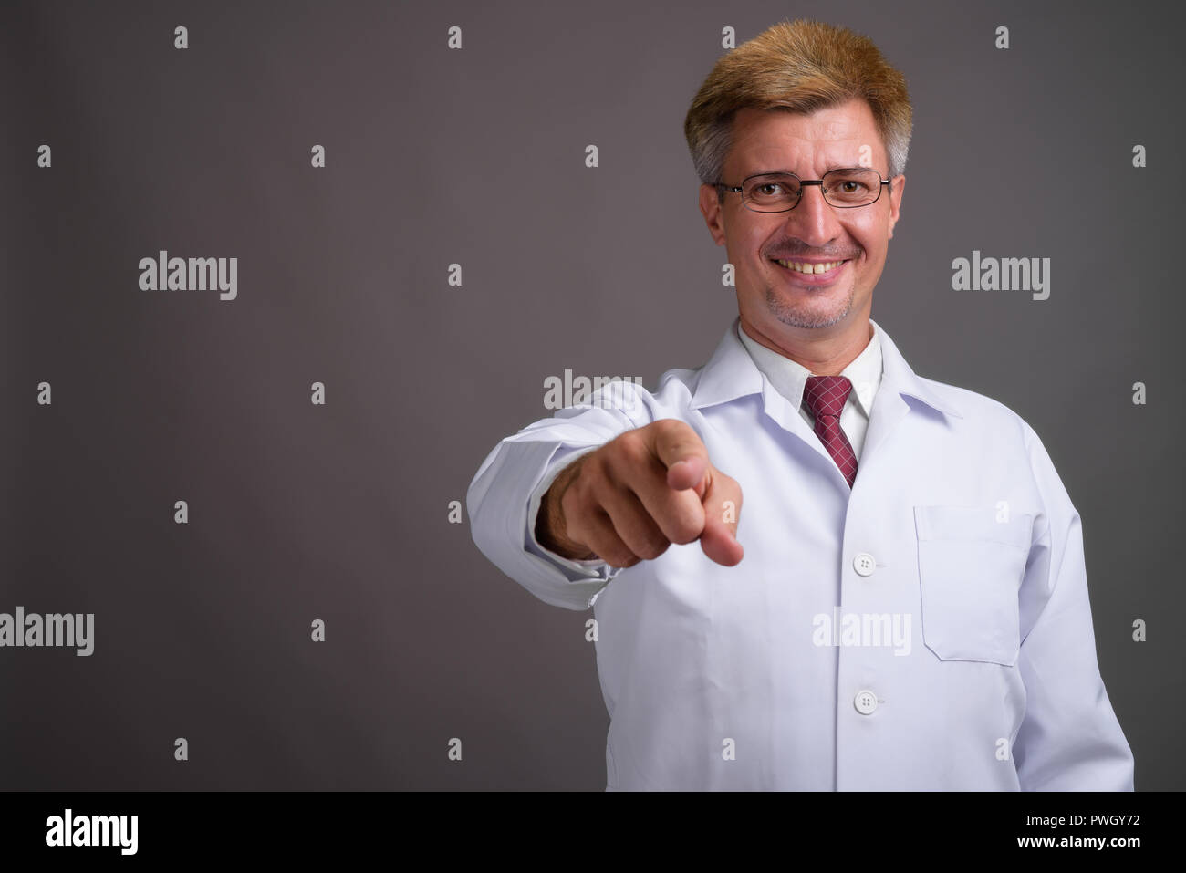 Médecin de l'homme aux cheveux blonds contre l'arrière-plan gris Banque D'Images