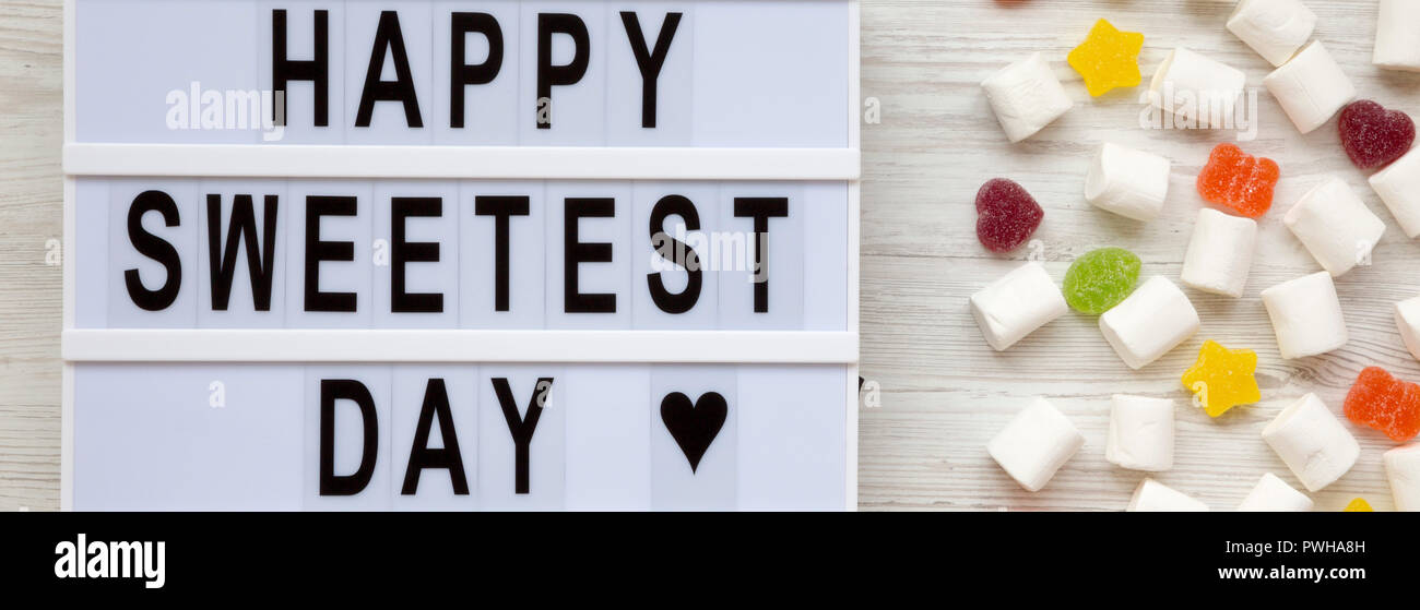 Lightbox avec texte 'Happy Day' plus doux et des bonbons sur un fond en bois blanc, vue du dessus. Mise à plat, d'en haut. Banque D'Images