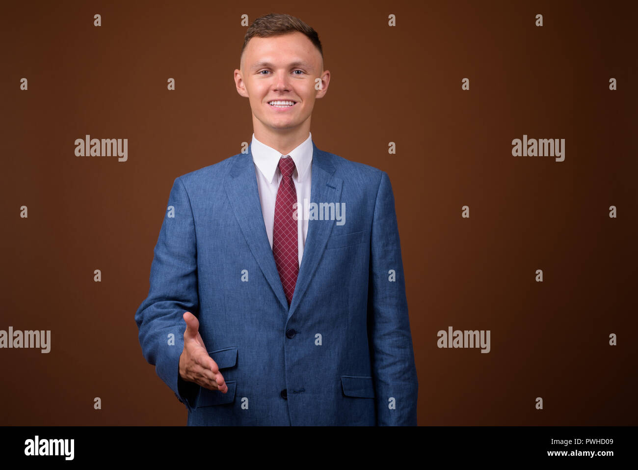 Young businessman wearing poursuite contre fond brun Banque D'Images