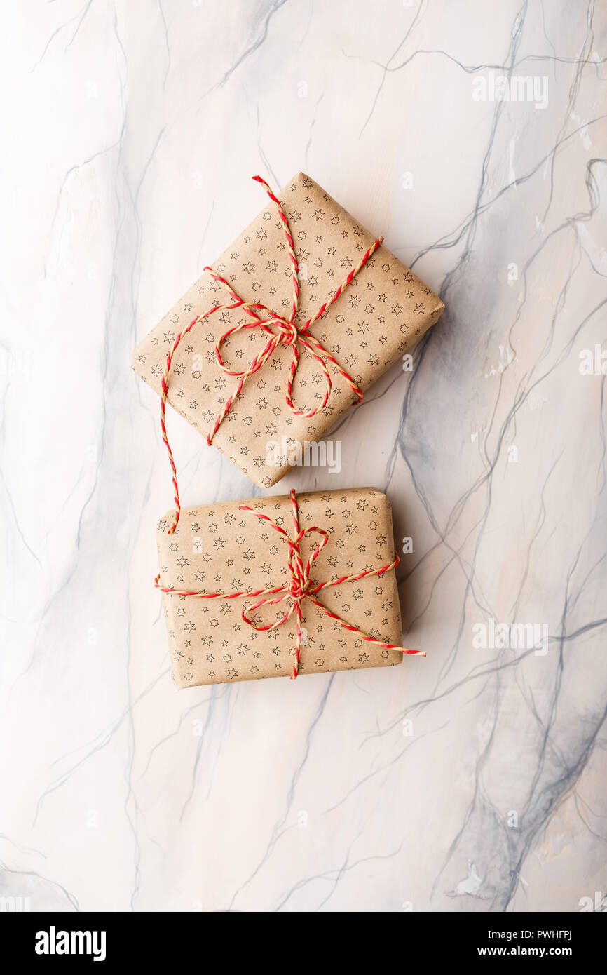 Deux boîtes de cadeaux emballés dans du papier craft sur fond de marbre rose Banque D'Images